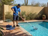 Technician skimming a residential pool in an arid courtyard